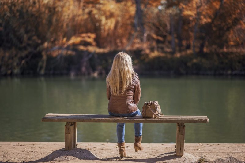 back view of woman on bench by water