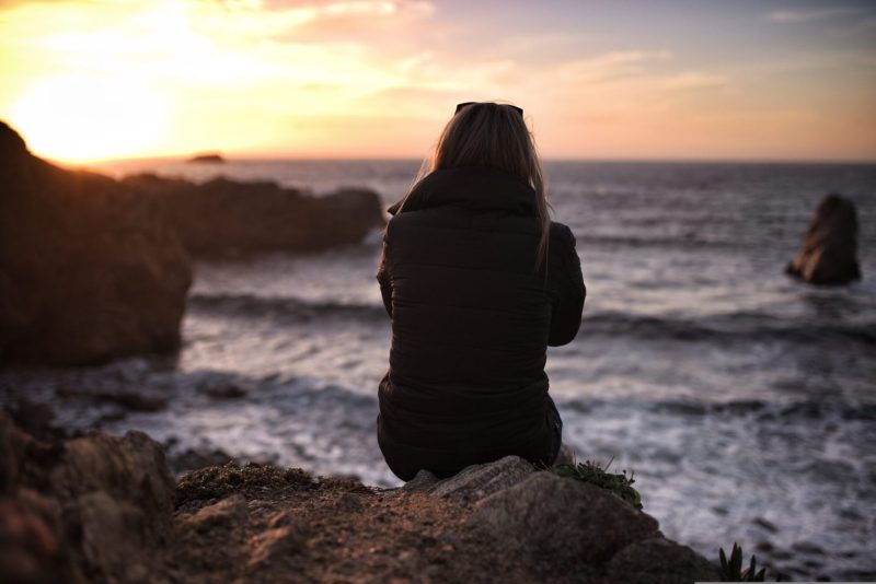 woman in down coat looking at ocear thinking divorce