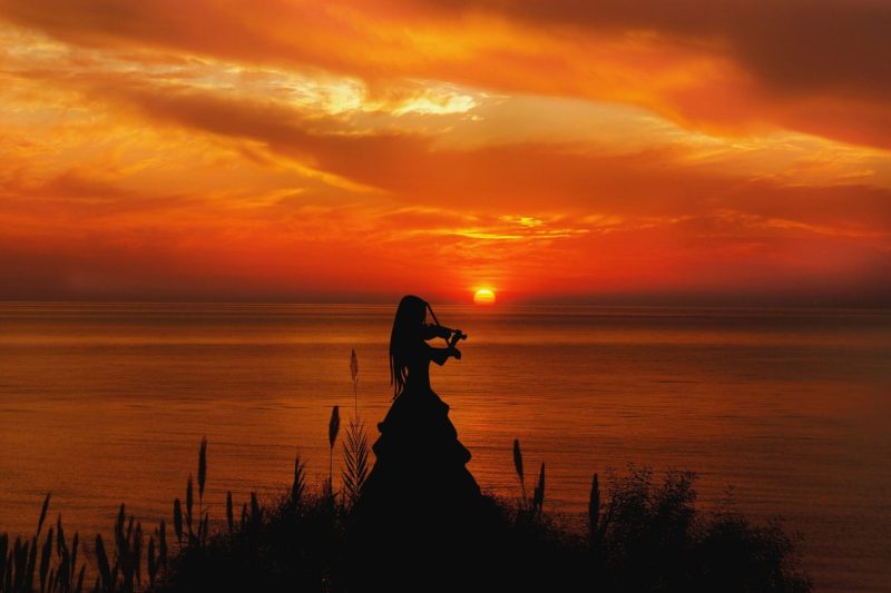 woman playing violin silhouette at beach sunset