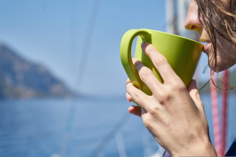 woman sipping coffee at beach looking left space for content