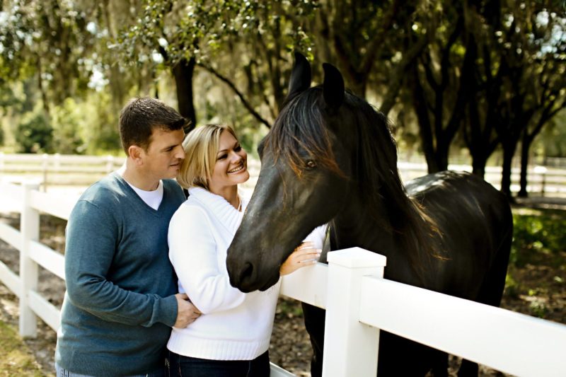 young couple with horse at white fence