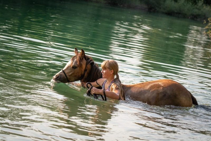 woman and horse in river or lake